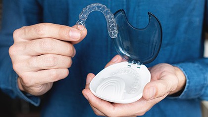 Closeup of patient putting clear aligner in case